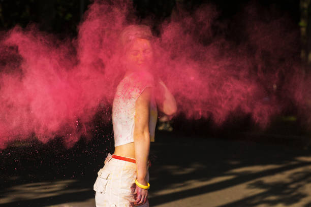 istock Adorable young woman playing with pink dry paint Holi exploding around her 1328198546