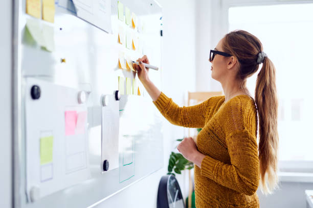 Young woman working in startup office writing on whiteboard stock photo