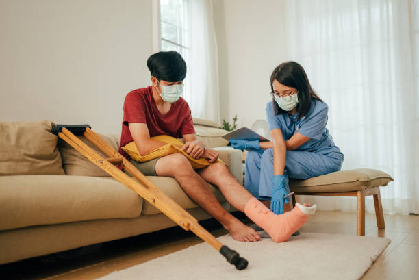 Nursing home. Female nurse bandages the patient's broken leg and monitors the condition at his home. stitches wound surgery nurse stock pictures, royalty-free photos & images
