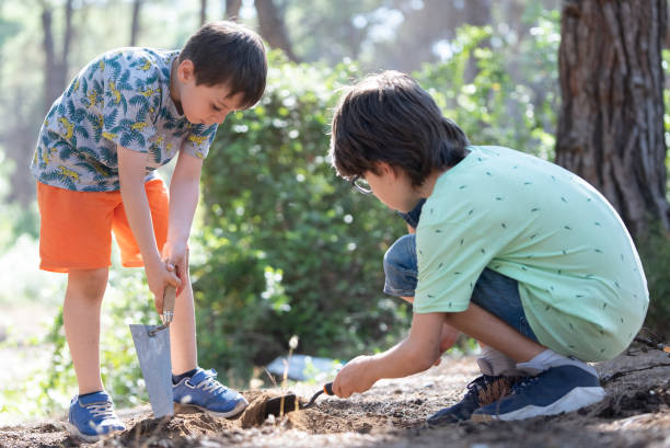 istock Two brothers sitting on grass playing with mud in forest 1328203510
