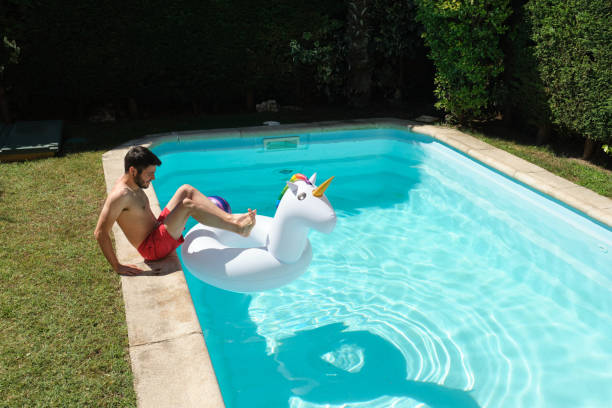 istock Young man going into the swimming pool through a big unicorn inflatable ring. Summer concept. 1328209189