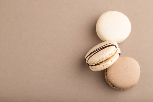 istock Brown and white macaroons on beige pastel background. top view, flat lay, copy space, still life. Breakfast, morning, concept. 1328209854