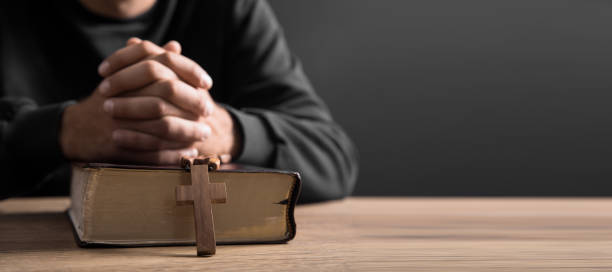istock prayer man holding cross with Bible 1328219916