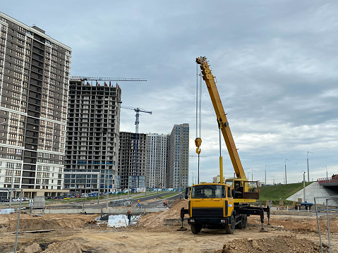 Large yellow mobility modern industrial construction crane mounted on a truck is used in the construction of new housing, houses, buildings in a big city.