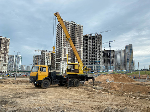 Large yellow mobility modern industrial construction crane mounted on a truck is used in the construction of new housing, houses, buildings in a big city.