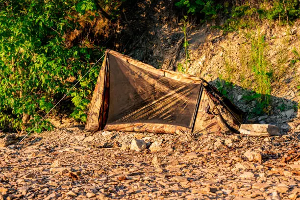 hiking camp on a rocky shore, small one-person tent