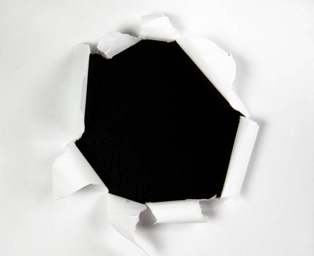 istock Hole in a Torn Paper over Black Background 1328221088
