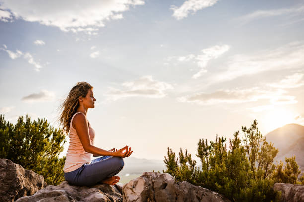 Young woman preforms yoga in mountains at sunset