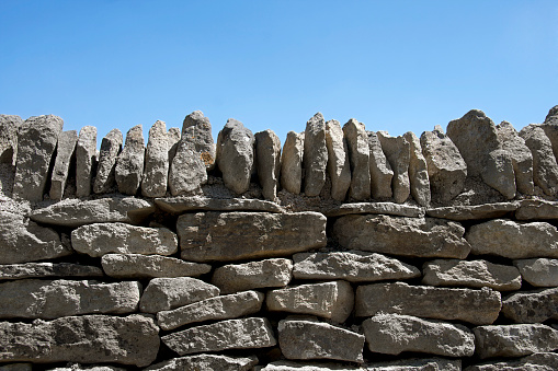 A dry stone wall against clear blue sky. Space for text.