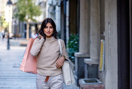Stylish Woman is Having Relaxing Walk in City Streets. A Woman is Enjoying in Autumn Afternoon in the City While Walking with Shopping Bags.