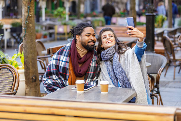 istock A Young Multi-Ethnic Couple is Spending a Wonderful Evening Together, Having a Lovely Communication and Sharing a Fresh Drink, and Taking Selfie Photos with Mobile Phone. 1328234615