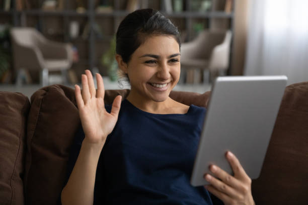 istock Close up smiling Indian woman waving hand, using tablet 1328237093