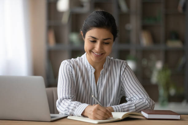 istock Close up smiling Indian woman taking notes, studying at home 1328237148