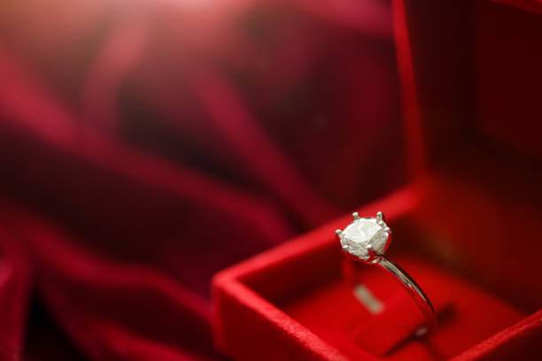 istock Diamond ring in jewelry gift box on red fabric background 1328237926