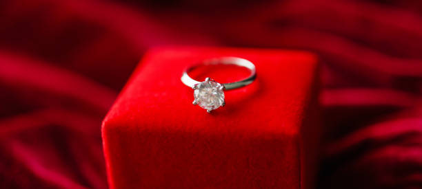 istock Diamond ring with jewelry gift box on red fabric background 1328237946