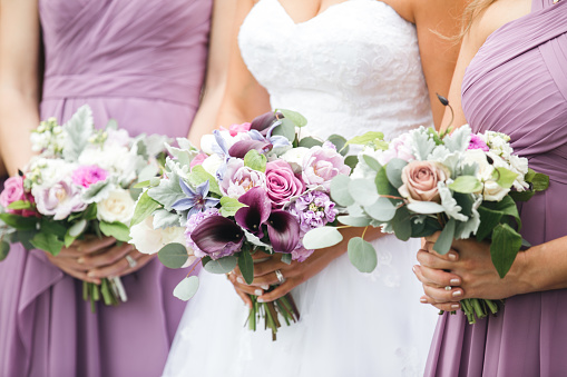 Damas de honor con vestidos rosas y vioilet con arreglos florales. CLose up de fiesta nupcial con ramos. photo