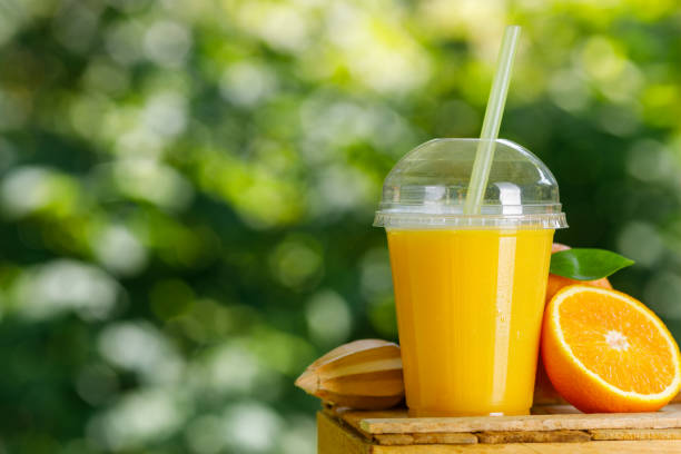 disposable plastic glass of cold freshly squeezed orange juice stock photo