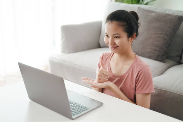 istock Young Asian woman deaf disabled using laptop computer for online video conference call learning and communicating in sign language. 1328269958