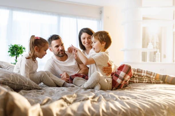 istock Happy parents and their kids talking on a bed. 1328272744