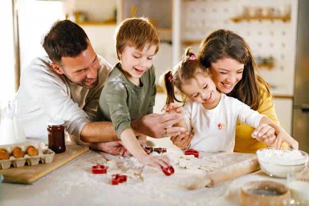 istock Happy parents and their kids cooperating while making cookies in the kitchen. 1328272882