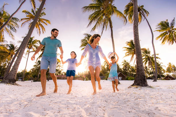 Carefree family running on the beach. Happy parents and their small kids having fun while holding hands and running on the beach in summer day. Copy space. beach holiday stock pictures, royalty-free photos & images