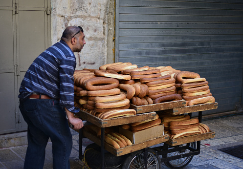 East Jerusalem, The Old City– July 10, 2021: In the early morning, a worker delivers all the bagels to sellers in the market.