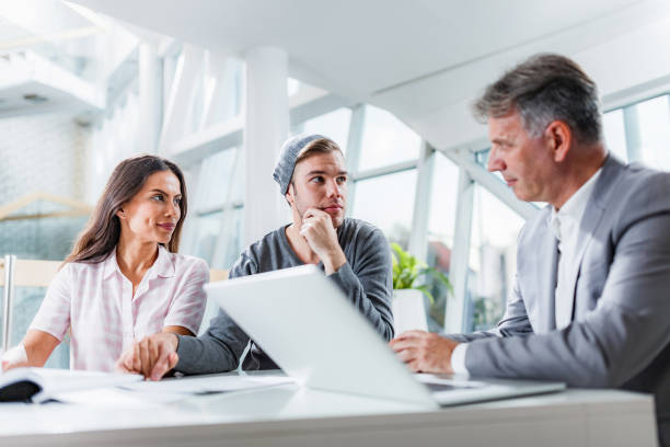 istock Young couple talking about plans with their insurance agent in the office. 1328276856
