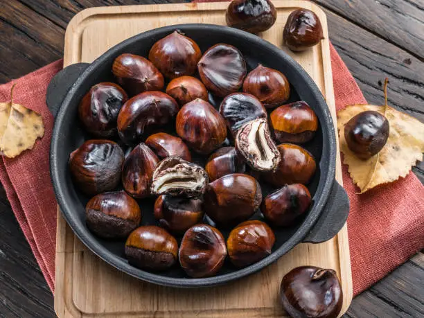 Photo of Roasted edible chestnut fruits in the pan. Top view.