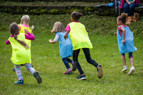 istock Young girls in distinguishing jerseys running on grass 1328280611