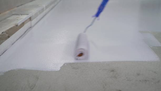 istock A worker paints the concrete floor with a roller white. Concrete Floor repair work. Paint roller in construction site 1328280884