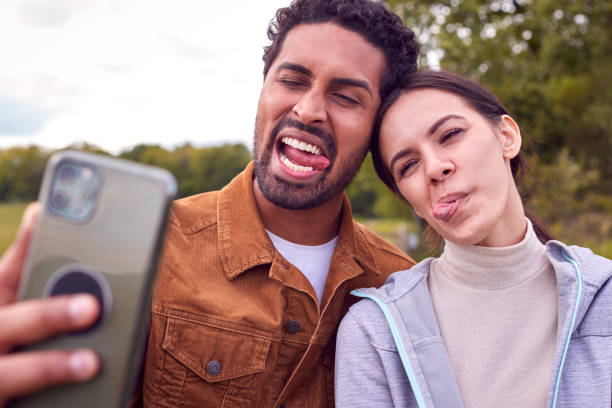 istock Couple On Walk In Countryside Pulling Funny Faces As They Take Selfie On Mobile Phone 1328282581