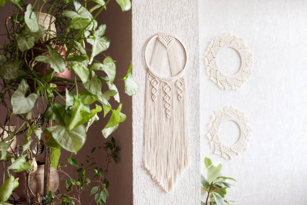 istock Handmade cotton macrame Dream catcher on white wall background. Traditional amulet for protecting sleep.  Macrame lace on the wall with green leaves 1328283249