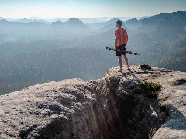 bosy mężczyzna w czerwonej koszulce z tripodem na skale. szwajcaria saksonia, dolina grosser zschand. - behind photographer men mountain climbing zdjęcia i obrazy z banku zdjęć