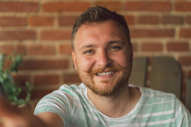 istock Handsome manly guy with beard and mustache looking in camera and takes a selfie. 1328286916