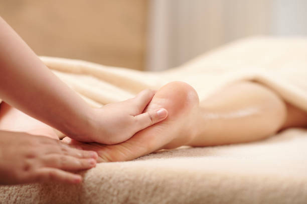 Relaxinf Feet Massage Hands of therapist massaging feet of young woman with moisturizing oils foot spa treatment stock pictures, royalty-free photos & images