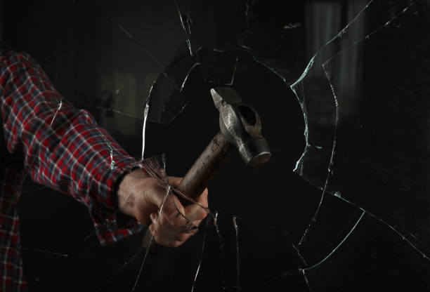 istock Man breaking window with hammer on black background, closeup 1328290040
