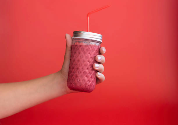 istock hand holds a jar of smoothies on a monochrome red background 1328295288