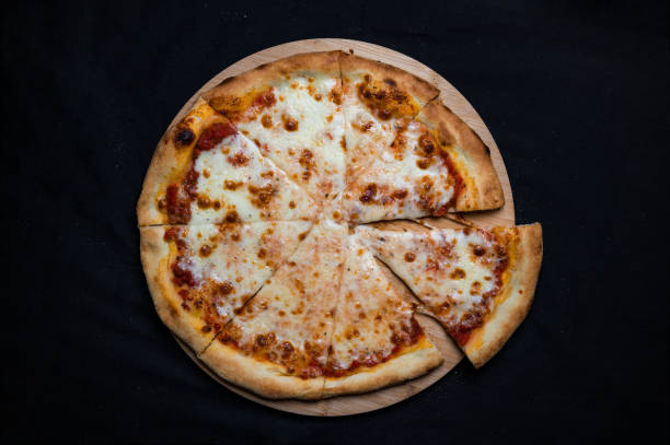 istock Pizza with tomato sauce and mozzarella cheese on a black background. 1328296530