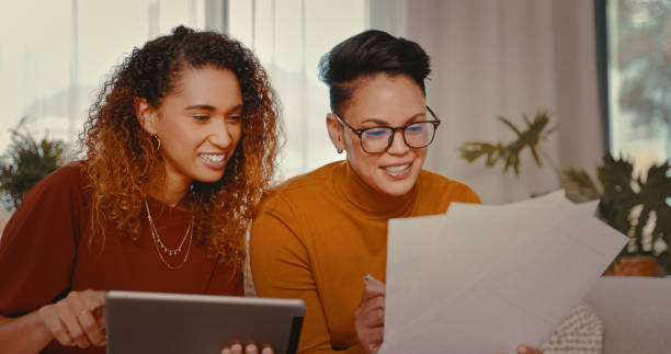 istock Shot of a young lesbian couple doing paperwork while using a digital tablet at home 1328296605
