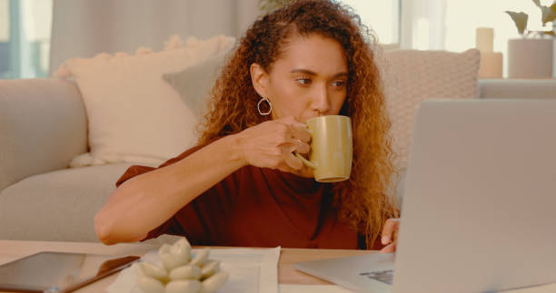 istock Shot of a young woman drinking coffee while using a laptop at home 1328296654