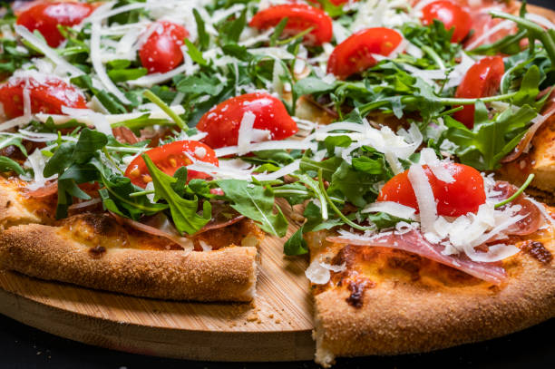 istock Pizza with tomato sauce, smoked pork muscles, mozzarella, arugula salad and cherry tomatoes on a black background. 1328296735