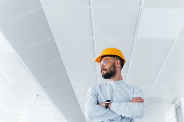 istock Portrait of engineer in white clothes and orange protective hard hat that standing and working indoors 1328297778