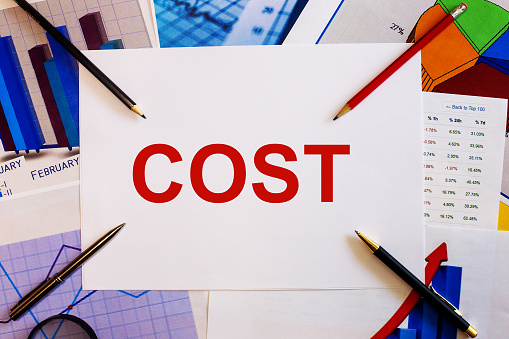 The cost is written on a white sheet near the pencils and graphs. Business concept