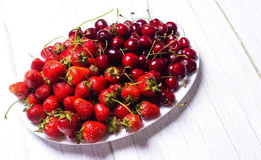 Ripe cherries and strawberries on a white dish