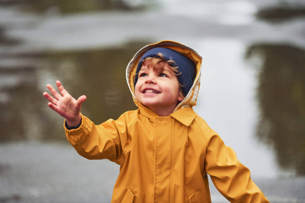 istock Kid in yellow waterproof cloak and boots playing outdoors after the rain 1328300479
