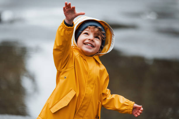 istock Kid in yellow waterproof cloak and boots playing outdoors after the rain 1328300576