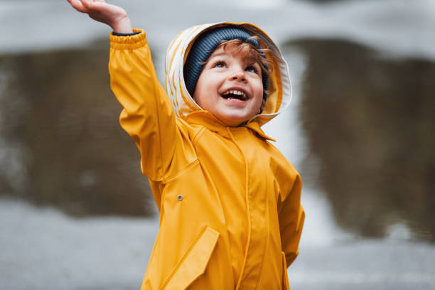 istock Kid in yellow waterproof cloak and boots playing outdoors after the rain 1328300581