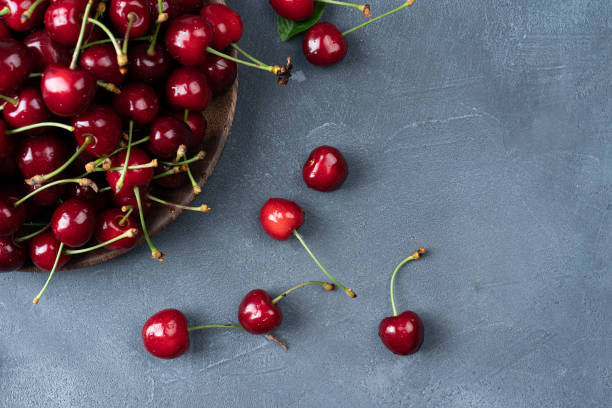 istock Cherries in a plate and scattered on a table cherries top view on a grey obsolete background 1328303034