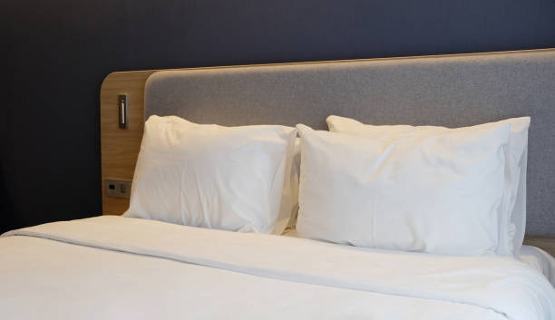 istock Close-up fragment of bedroom with empty bedside table, reading lamp and USB socket in modern interior​ design home or hotel. Soft pillow and blanket, stylish comfortable furniture. 1328303246