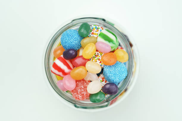 caramelle assortite in un barattolo di vetro su sfondo bianco. vista dall'alto. - gelatin dessert multi colored vibrant color celebration foto e immagini stock